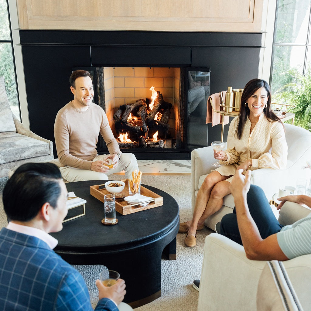 couple entertains with cocktails around fireplace