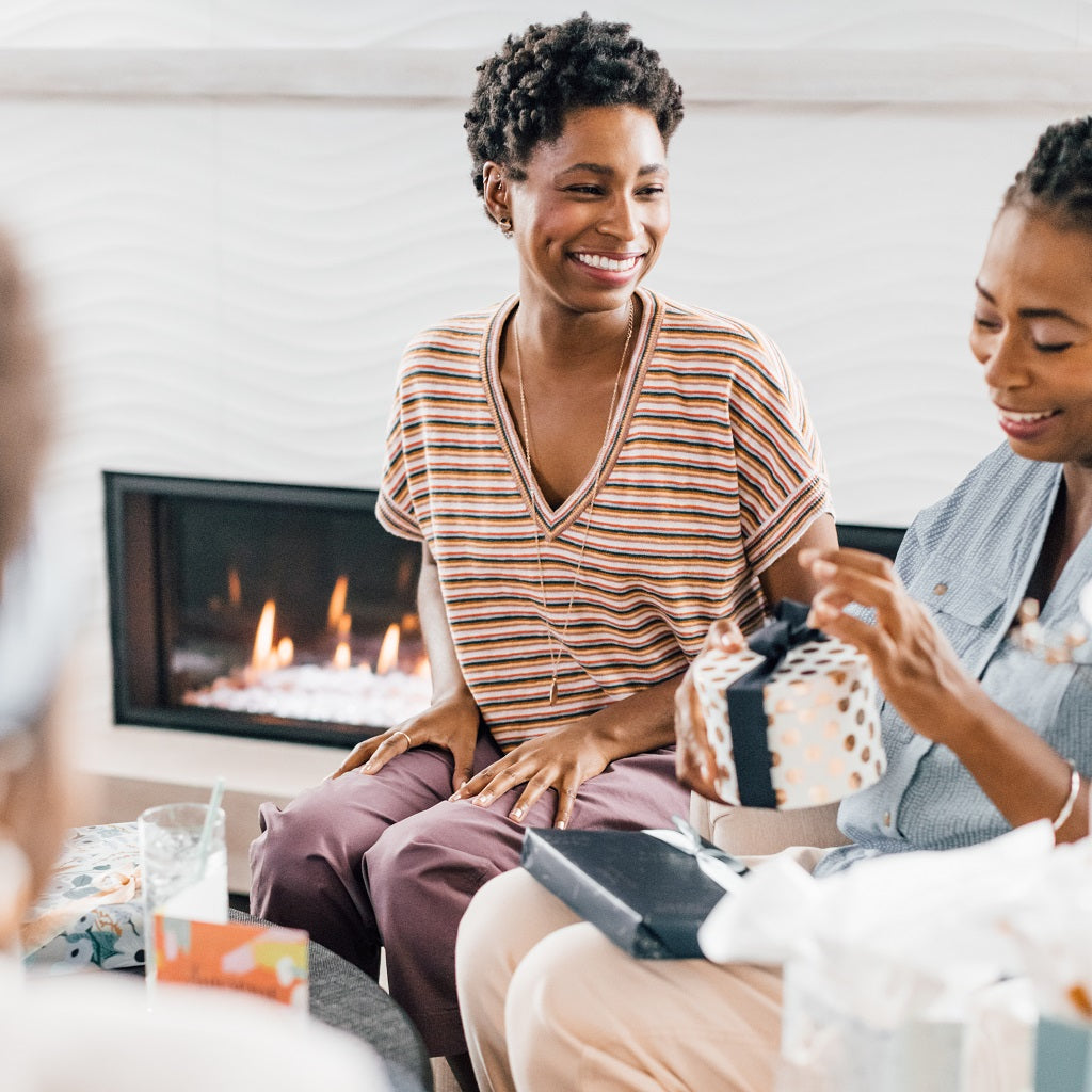 woman and granddaughter open gifts around modern fireplace