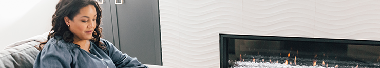 A woman reading in front of her fireplace