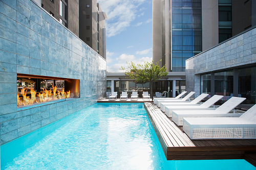 custom outdoor see-through gas fireplace pool with white pool chaise lounges downtown